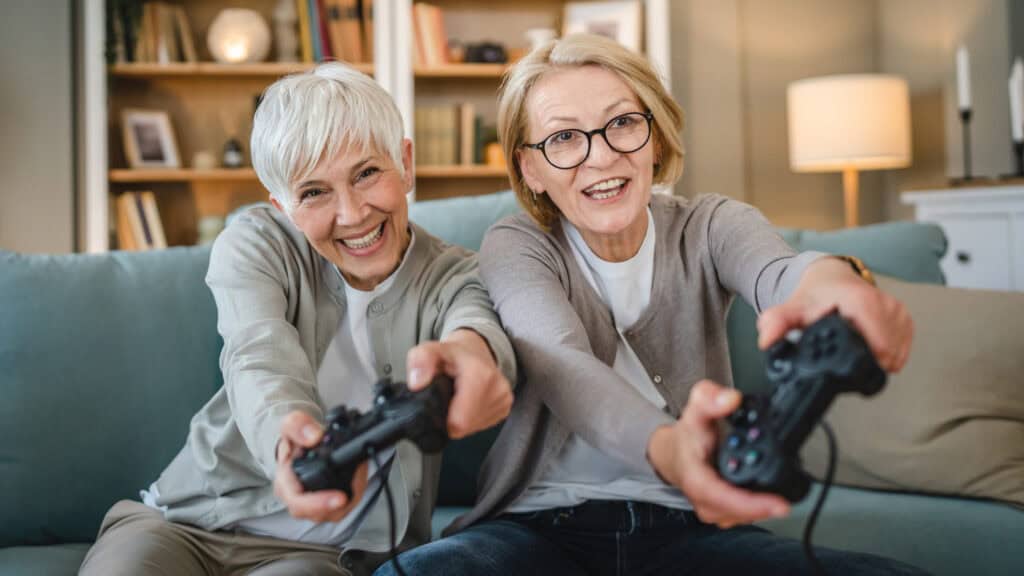Two senior women friends or sisters playing video games
